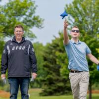 Two players stand throwing bags during a game